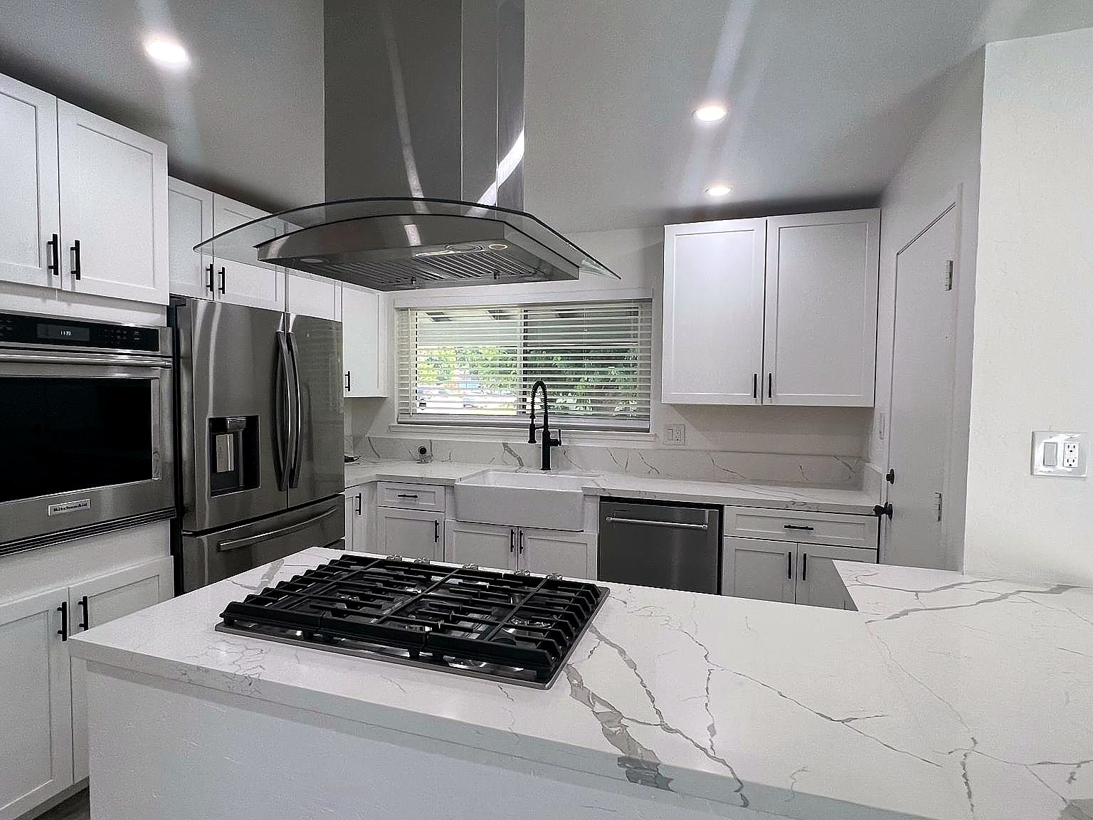 Remodeled kitchen with white cabinetry and stainless appliances